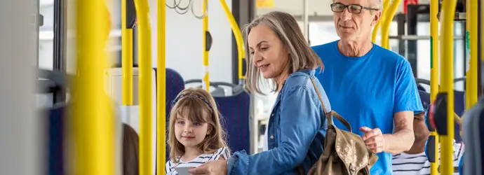 Gyermekes család száll fel a buszra, sárga síneken.