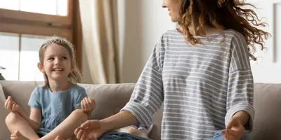 Nő és gyermek ül meditációs helyzetben egy kanapén.