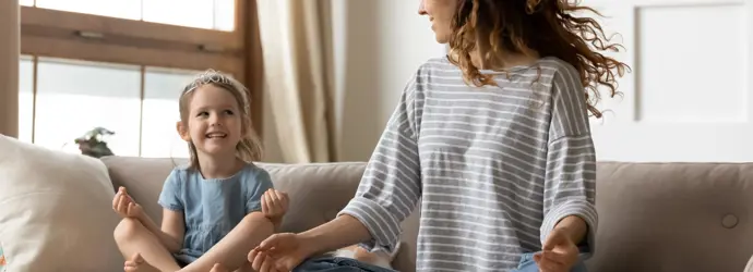 Nő és gyermek ül meditációs helyzetben egy kanapén.