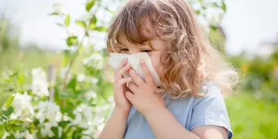 Egy kislány fújja az orrát, hogy enyhítse a pollenallergia tüneteit